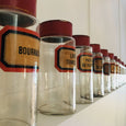 Grand pot de pharmacie en verre soufflé avec étiquette et couvercle en fer peint rouge